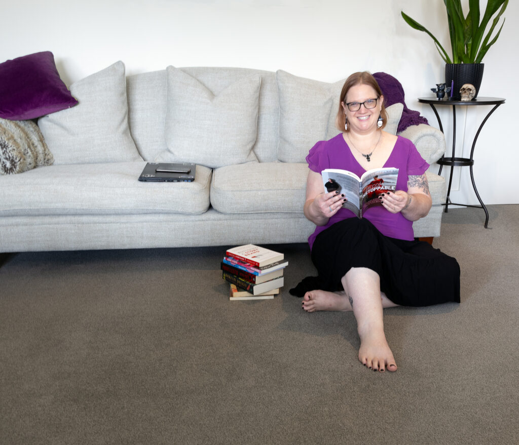 Louise McKay - Fractional Newsletter Manager - sitting on the floor with a stack of business help books