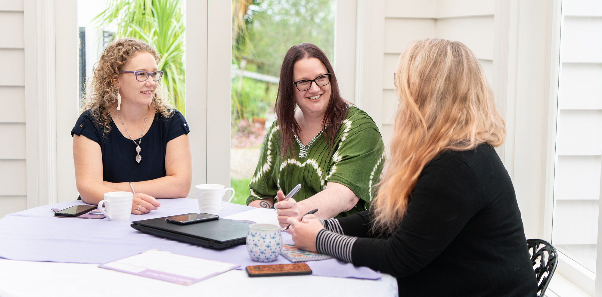 3 women sitting at a table having a business meeting